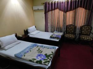 una camera con due letti e due sedie di Paramount Guest House a Islamabad