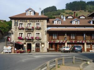 a building on a street with cars parked in front of it at Hosteria Peña Sagra in Ojedo