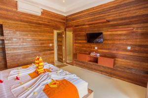 Schlafzimmer mit Holzwänden und einem Bett mit TV in der Unterkunft Dinatah Lembongan Villas in Nusa Lembongan