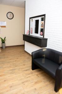 - un canapé en cuir noir dans une chambre avec une horloge dans l'établissement Monada Hotel & Hostel, à Oujhorod