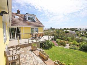 a yellow house with a deck and a patio at Windrush in Newquay