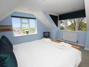 a bedroom with a large white bed with two windows at Windrush in Newquay