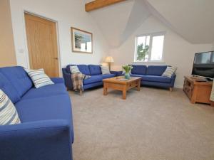 a living room with blue couches and a tv at Penhaven in Bude