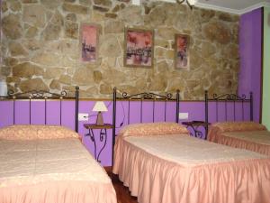 1 dormitorio con 2 camas y pared de piedra en Hosteria Peña Sagra, en Ojedo