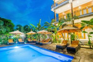 ein Swimmingpool mit Stühlen und Sonnenschirmen neben einem Gebäude in der Unterkunft Dinatah Lembongan Villas in Nusa Lembongan