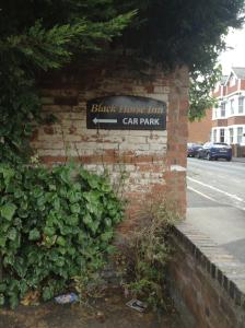 a brick wall with a sign for a car park at The Black Horse Inn in Warwick