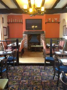 uma sala de jantar com mesas e uma lareira com uma televisão em The Black Horse Inn em Warwick