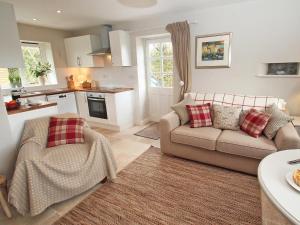 a living room with a couch and a kitchen at Stocks Barn in Liskeard