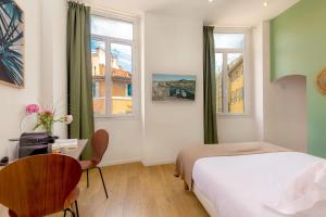 a bedroom with a bed and a desk and two windows at Breteuil – Appart au Vieux Port in Marseille
