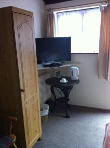 um quarto com uma mesa com uma televisão e uma mesa com um tvictericter em The Black Horse Inn em Warwick