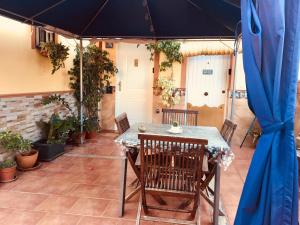 a table with chairs and a blue umbrella on a patio at Cool Garden and Suite Terraza íntima y calma en Mairena del Aljarafe in Mairena del Aljarafe