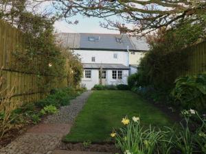 a garden with a white house and a fence at Halvosso in Penryn