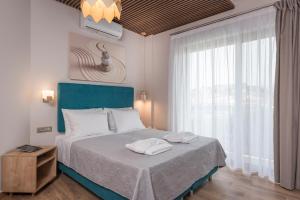 a bedroom with a bed with a blue headboard and a window at Aequor Luxury Rooms & Apartments in Kato Daratso +137 photos
