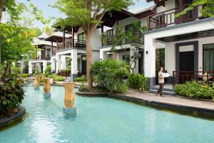 a woman standing next to a swimming pool in front of a building at The Zign Hotel Premium Villa in North Pattaya