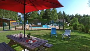 a picnic table with a red umbrella next to a pool at VVF Aubrac in Chaudes-Aigues