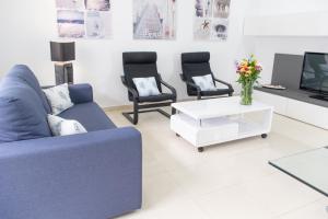 sala de estar con sofá azul y 2 sillas en Apartamento Montroig 2, en Sitges