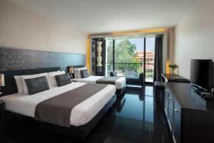 a hotel room with two beds and a television at Way Hotel Pattaya in North Pattaya