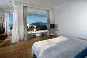 a bedroom with a white bed and a large window at Relais Blu in Massa Lubrense
