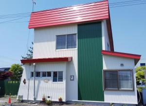 a white and green house with a red roof at Minshuku Kaikazari Kunnui in Oshamambe