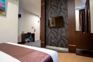 Habitación de hotel con cama y TV en la pared en Orkid Inn Mahkota Cheras en Kampong Perimbun