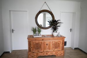 a mirror on top of a wooden dresser with plants on it at Ferienwohnung Zeilfelder in Hirschberg an der Bergstraße