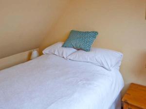 Solas في Isleornsay: سرير ابيض عليه وسادة زرقاء