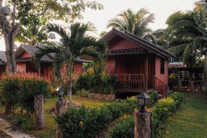 una pequeña casa roja con palmeras delante en Cocco House, en Ao Nang Beach