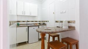 a kitchen with white cabinets and a marble counter top at Las Faluas in Playa del Ingles