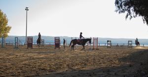 a group of people riding horses in an arena at Athlos Hotel in Thessaloniki