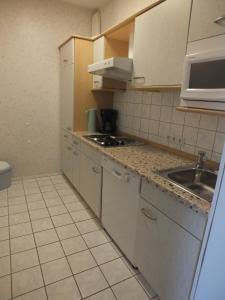 a small kitchen with a sink and a microwave at Ferienwohnungen Hüning in Grömitz