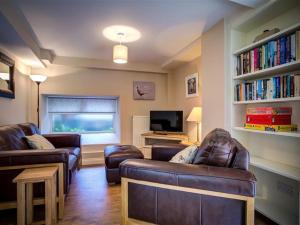 a living room with two leather couches and a tv at Mill Race in Burford