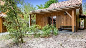 een houten huis met een veranda en een boom bij Vacancéole - Les Rives du Lac in Lacanau