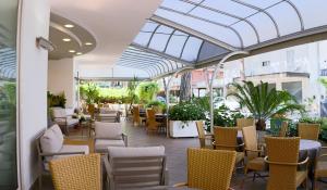 a conservatory with chairs and tables in a building at Hotel Myosotis in Riccione