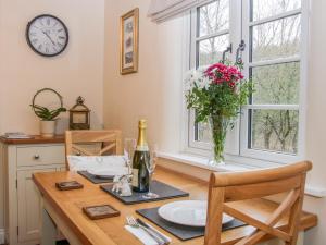 una mesa de comedor con un jarrón de flores y un reloj en Tub Boat Cottage en Telford