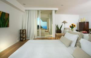 a white bedroom with a large bed and a living room at Relais Blu in Massa Lubrense