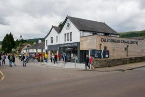 people walking down a street next to a building at Lock Chambers, Caledonian Canal Centre in Fort Augustus