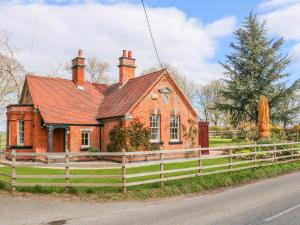 a red brick house with a fence in front of it at South Lodge - Longford Hall Farm Holiday Cottages in Ashbourne