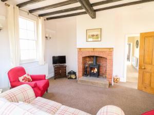 a living room with a fireplace and red chairs at South Lodge - Longford Hall Farm Holiday Cottages in Ashbourne