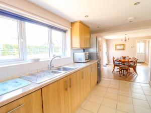 eine Küche mit Holzschränken und einem Tisch mit einem Esszimmer in der Unterkunft Ardsley Cottage - Longford Hall Farm Holiday Cottages in Ashbourne