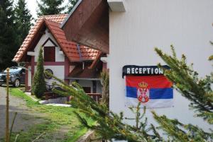 ein Schild an der Seite eines Hauses mit einer Flagge in der Unterkunft Vile M&S in Kopaonik