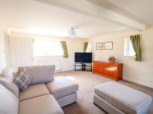 a living room with a couch and a tv at Ardsley Cottage - Longford Hall Farm Holiday Cottages in Ashbourne