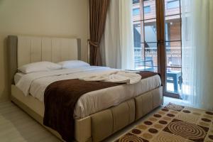 a bedroom with a large bed with a balcony at Uzungöl Kuzey Park Pansiyon in Uzungöl