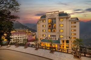 a hotel building with a sunset in the background at Pistachio Hotel Sapa in Sapa