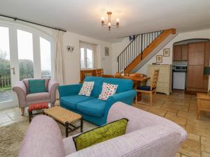 uma sala de estar com um sofá azul e cadeiras em The Coach House em Shepton Mallet