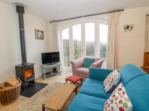 a living room with a blue couch and a wood stove at The Coach House in Shepton Mallet
