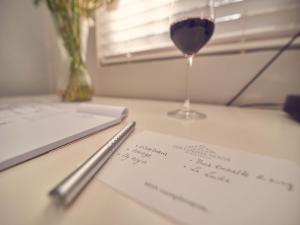 a glass of wine and a piece of paper on a table at Corner House Residence in Franschhoek