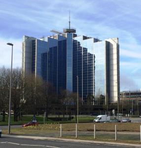 a large glass building with a car parked in front of it at Churchill Place - Downtown Luxury Apartments in Basingstoke