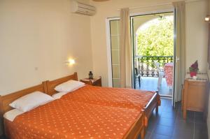 una camera da letto con un letto e un piumone arancione di Holiday Apartment yannis on the beach of Agios Gordios in Corfu ad Agios Gordios