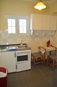 a kitchen with a sink and a stove and a table at Holiday Studio Apartments yannis on the beach of Agios Gordios in Corfu in Agios Gordios