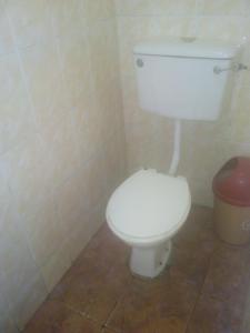 a bathroom with a white toilet and a trash can at Rising Phoenix in Accra